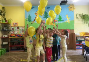Dzieci podnoszą do góry żółte balony